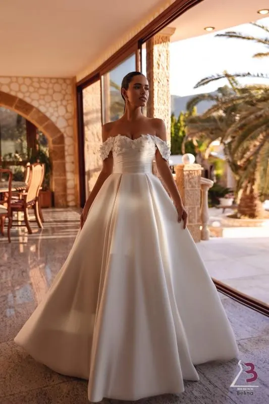 Noiva com vestido de cetim ombro a ombro num pátio com arcos