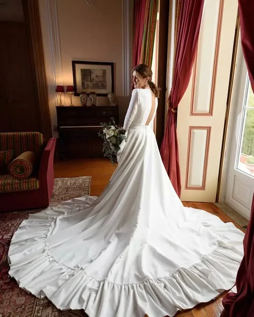 Noiva de costas com vestido de cauda longa num salão antigo